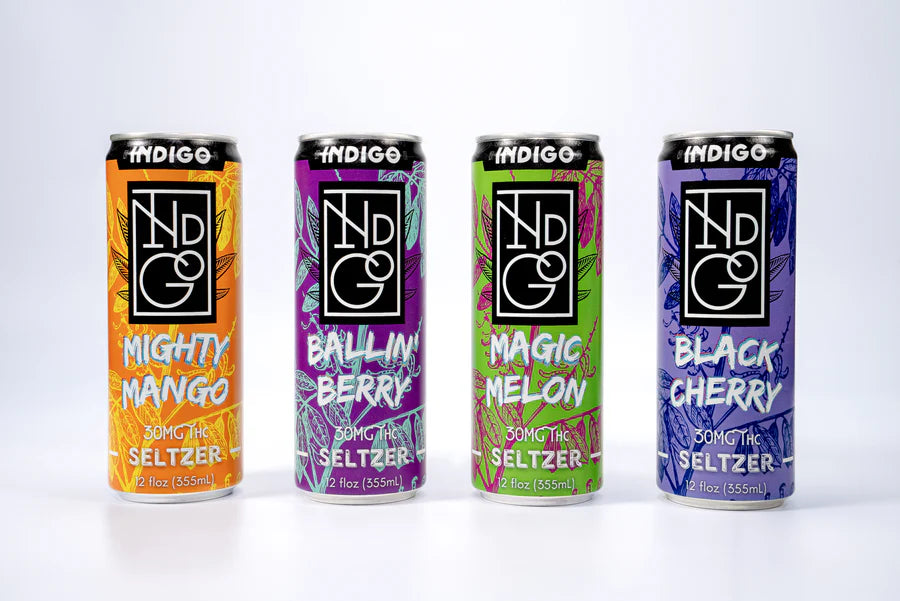 Four cans of Indigo Seltzer with different flavors on a white background